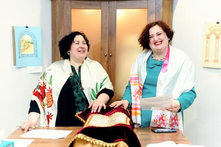 Two women at the bimah with a Torah scroll in front of them