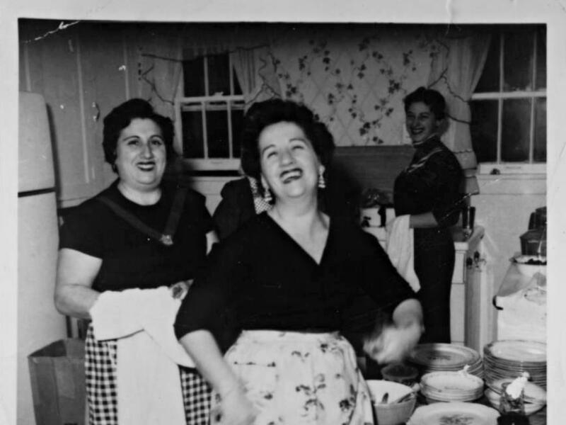 Black and white photo of three women laughing in a kitchen