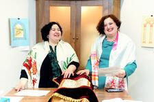 Two women at the bimah with a Torah scroll in front of them