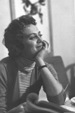 Hanna Maron sitting at a table, smiling with her chin in her hand