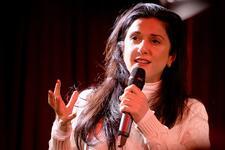 Dorit Rabinyan gesturing as she speaks into a microphone