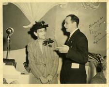 a signed photograph of Ida Weis Friend speaking to deLesseps Morrison standing beside a microphone