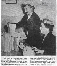 Lillian Freehof types on a Braille machine while another woman files paperwork behind her