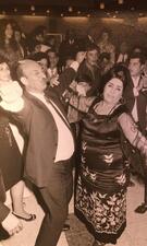 Zohra El Fassia dancing with her nephew Uri Hayon (left), whose arms are extended in the air in joy, in the middle of a crowd