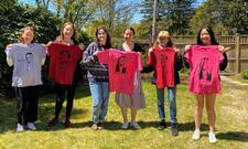 Rising Voices Fellows holding up T-shirts with feminists on them