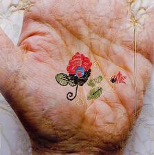 Photograph of a hand with flower embroidered on it