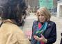 One woman with her back to camera holds out a recorder to interview an older woman