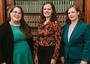 Photo of three women standing in front of a bookcase