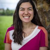 Photo of Lilah Peck, in front of tree wearing geometric shirt with a white, orange, and pink pattern.