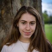 Photo of Dahlia Soussan, in front of a tree wearing a white shirt with an illustrated flower pattern.