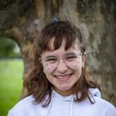 Photo of Hannah Landau, in front of a tree wearing a white hoodie.