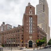 A brick building with a tower, situated on a street corner in New York City