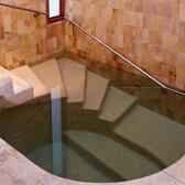 Interior of Mayyim Hayyim mikveh in Newton, Massachussetts showing stairs with handrail going into the water