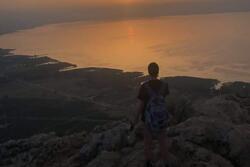 Sunrise over the Kinneret in Israel. Figure in the foreground on rocks.