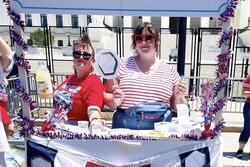 Two women stand at a booth with a sign that says "Abortion Pills"