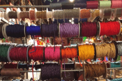 Rising Voices Fellow Caroline Kubzansky Behind Spools of Thread and Other Materials