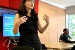 Woman talking and standing in front of slide presentation