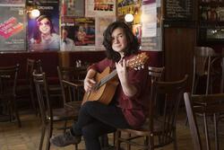 Young woman with dark hair sitting and holding guitar