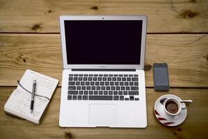 Desk with computer, coffee, notebook, and phone on top