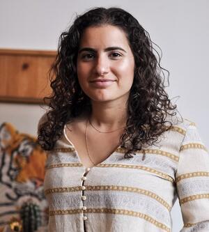 Erez Zobary is smiling at the camera, she has curly brown hair and is wearing a striped top.