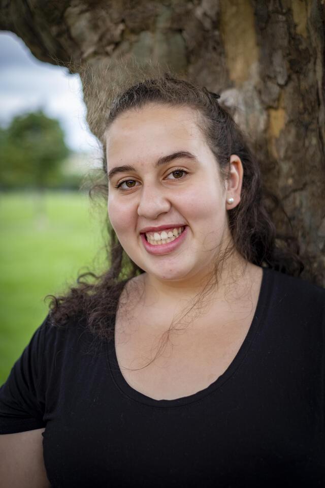 Photo of Ellie Klibaner-Schiff, in front of a tree wearing a black shirt.