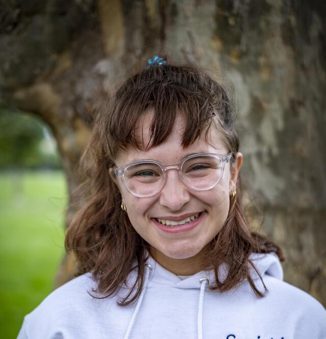 Photo of Hannah Landau, in front of a tree wearing a white hoodie.