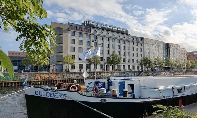 A ship with the word Goldberg inscribed, docked in the river