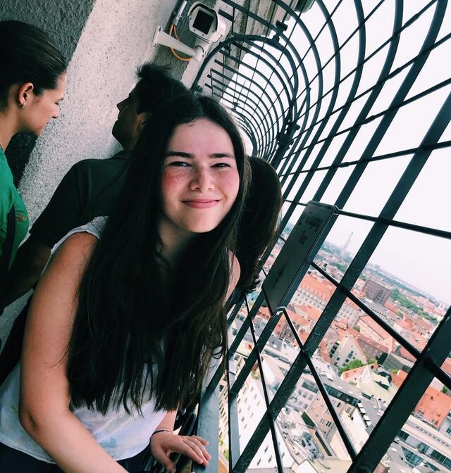 Ilana Drake standing in a passageway on the Bell Tower of St. Paul's Church, Munich cityscape below.