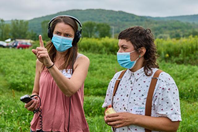 Woman with headphones and mic talks to another person