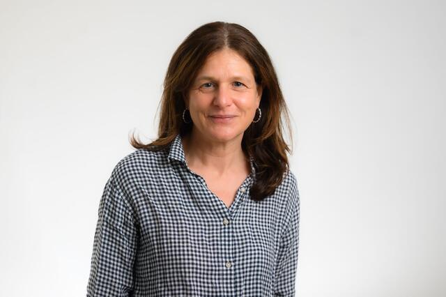 Middle-aged women in button down shirt with long dark hair, against white background